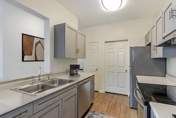 A kitchen with a sink, stove, and cabinets.